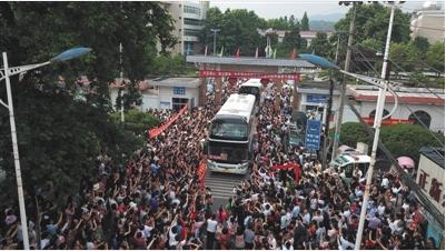 6月5日,安徽毛坦厂中学北门外,载着考生的大巴车缓缓驶出学校,考生家长夹道相送。当天,该校学生乘坐学校安排的大巴车前往六安市区准备高考。 新京报记者 王飞 摄