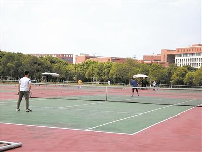 学生在网球场打网球。