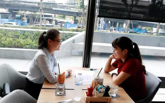 何婷(左)在曼谷一家咖啡馆和一名中国留学生温习功课。(路透社)