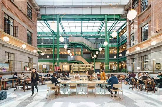 WeWork位于上海威海路路的办公空间,人们在开放工位上工作