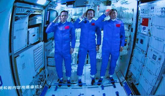 Screen image captured at Beijing Aerospace Control Center, June 17, 2021 shows three Chinese astronauts onboard the Shenzhou-12 spaceship saluting after entering the space station core module Tianhe. (Xinhua/Jin Liwang)