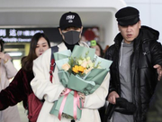 组图：李宇春现身机场获粉丝赠花 穿浅色风衣秀大长腿