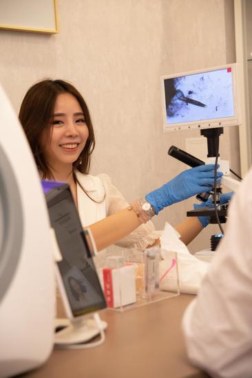 美容师通过美容测试仪帮助感兴趣的来宾深入了解自己的肌肤状态。