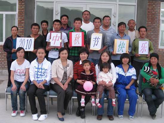 2010年,种植工人家庭与庄主陈立忠(前排正中)共度中秋,庄主怀抱阿不拉·吐尔逊当时两岁的大女儿
