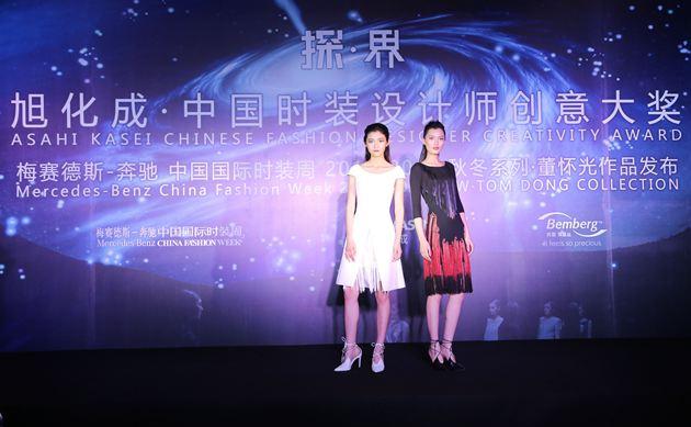 模特马熠晗、刘春杰在新闻发布会现场展示获奖设计师作品