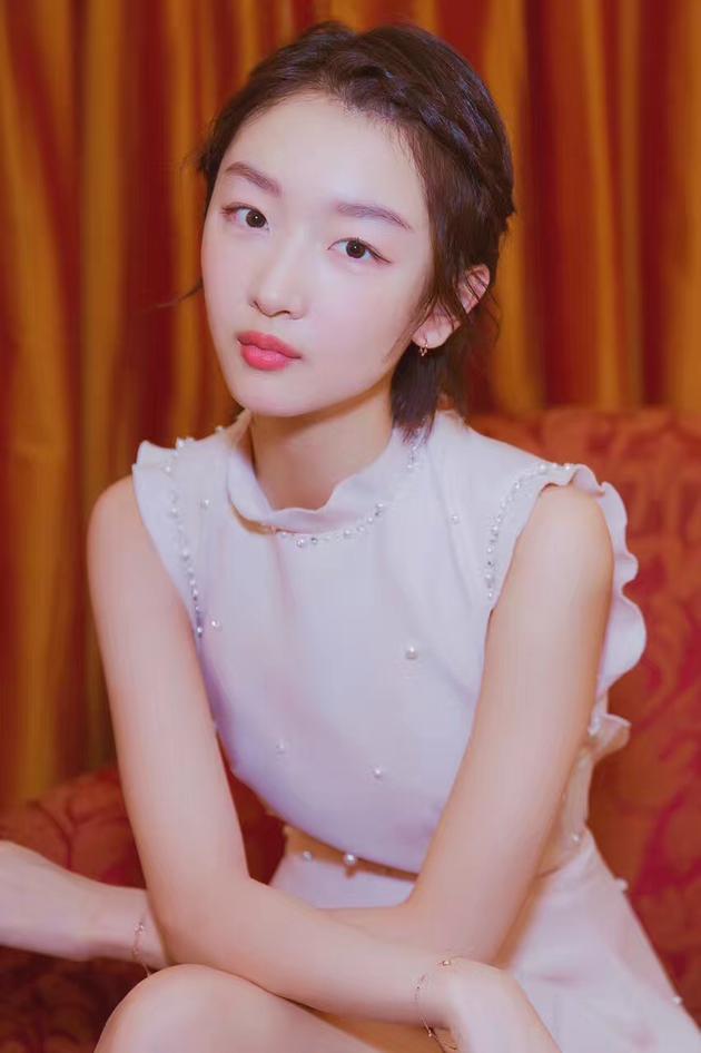 周冬雨身着Miu Miu 2017秋冬系列珍珠装饰白色连身短裙和高跟鞋,佩戴Didier Dubot高级珠宝亮相时尚活动。