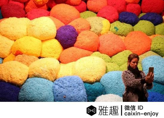 威尼斯双年展上一位观众在美国艺术家雪拉·希克(Sheila Hicks)的毛毡艺术品前自拍(图片来源于Telegraph)