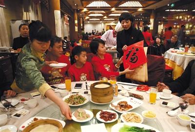 除夕夜,老字号全聚德前门店,一位工作人员为吃年夜饭的客人送上“福”字祝贺新年。