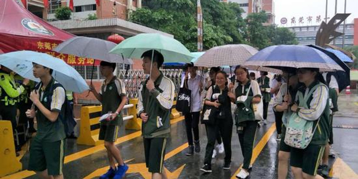 高考第一科语文考完了 东莞考生撑着雨伞走出
