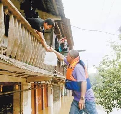 7月2日,在广西融安县受灾区,水位缓慢回落之际,当地青年干部正在给受灾群众送去食品。