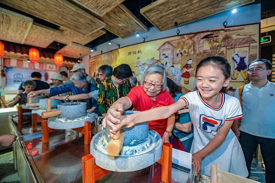 市民们体验磨豆制浆工艺。