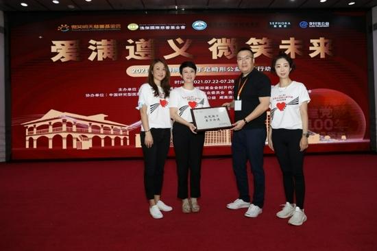 丝芙兰企业代表们从微笑明天慈善基金会副理事长靳玉洁先生手中接过“微笑接力,美力传递”牌匾