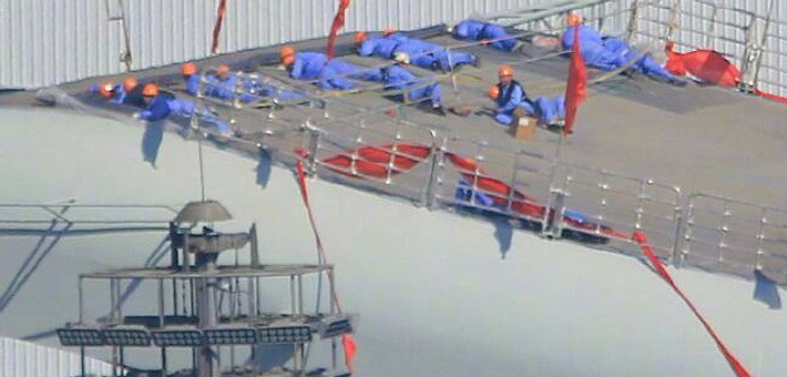 国产航母继续施工:工人们趴在舰艏操作