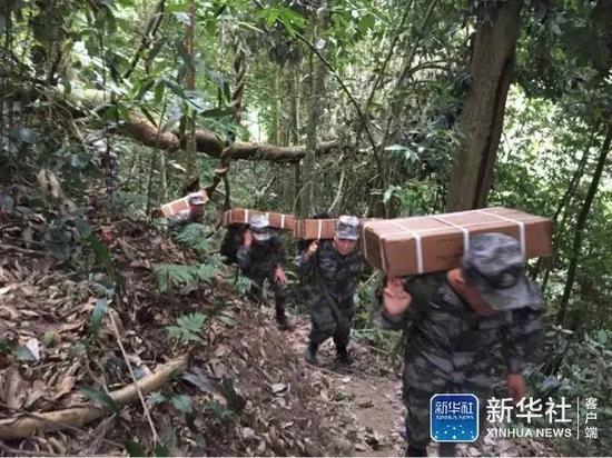 进入雷区后,排雷队员们穿戴好防护装备,肩扛炸药进入雷场。