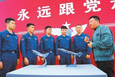 ▶4月17日,歼—20战机首飞试飞员李刚在与空军航空兵某旅“90后”飞行员交流。刘歆摄