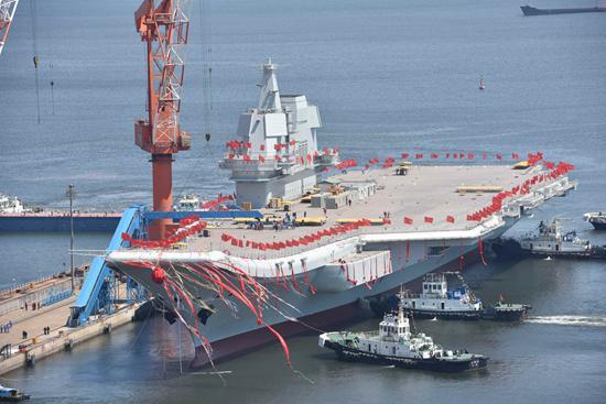 2017年4月26日,我国第二艘航空母舰下水仪式在中国船舶重工集团公司大连造船厂举行。图为航空母舰在拖曳牵引下缓缓移出船坞,停靠在码头泊位。视觉中国供图