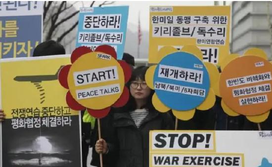 ▲2016年3月7日,在位于韩国首尔的美国驻韩国大使馆附近,韩国民众高举反战标语牌抗议韩美军演。图/新华社