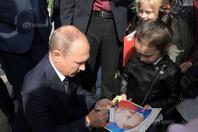 俄总统普京走访西伯利亚地区 蹲地给小迷妹签名
