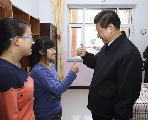 △2014年1月28日,习近平总书记在内蒙古呼和浩特市儿童福利院宿舍向聋哑女孩王雅妮(左二)和放假“回家”的大学生闫志净学习哑语“谢谢”。