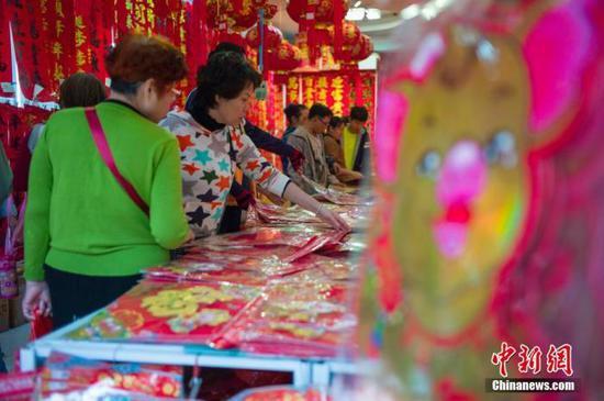 资料图:正值中国民间传统的“小年”,海南海口大街小巷的“年味”渐浓。图为市民选购福字(中新社记者 骆云飞 摄)