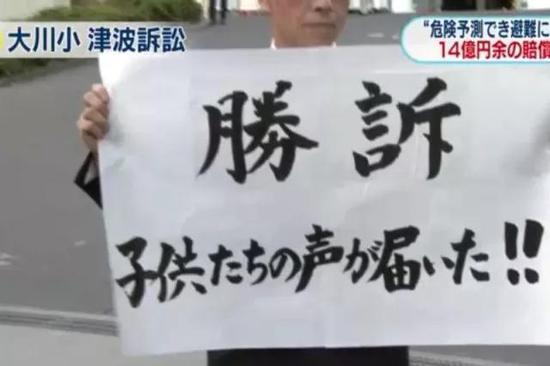 大川小学震灾过失案结果出炉,胜诉的父母高举告示牌。