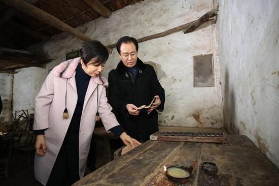 许家印和妻子丁玉梅在堂屋看着老物件回忆:“小时候条件很苦,每天晚上都是点着煤油灯,趴在这个小方桌上写作业。”
