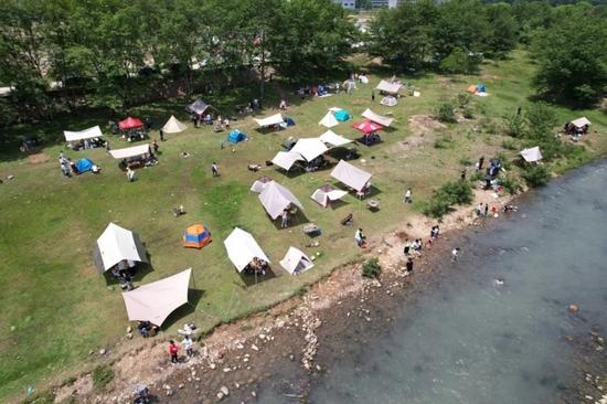 5月3日,游客在浙江省瑞安市湖岭镇天长村溪边搭帐篷露营(无人机照片)。图片来源:新华社发(庄颖昶摄)