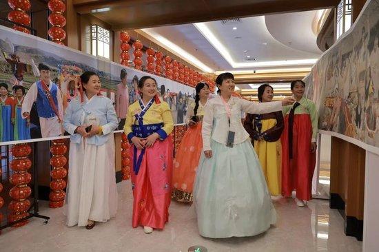 摄影爱好者身着朝鲜族民族服饰观看展览《吾土吾民》。