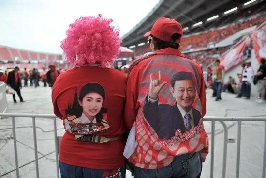 2013年11月30日,在泰国首都曼谷的拉加曼加拉国家体育场,两名“红衫军”分别穿着印有英拉头像和他信头像的上衣 图:新华社