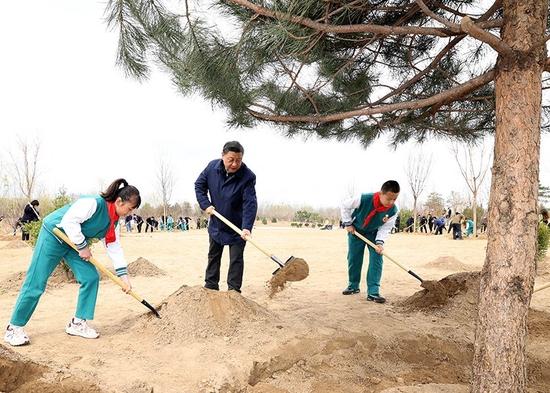 2022年3月30日,习近平等党和国家领导人来到北京市大兴区黄村镇参加首都义务植树活动。这是习近平同大家一起植树。