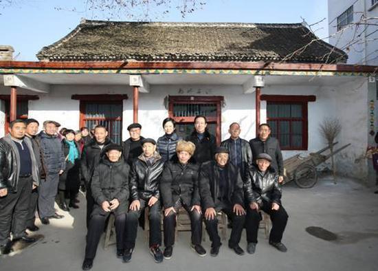 许家印和妻子丁玉梅回到太康县高贤乡聚台岗村,和长辈、小时同伴在自家院子里合影。