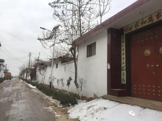 ▲李忠山家的房子目前大门紧闭,往西看去,路上大车对面就是任艳红家,两家距离五十米左右。 新京报记者 赵朋乐 摄