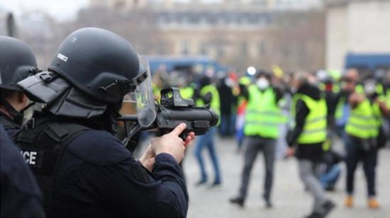 一名持枪法国警察瞄准示威者。