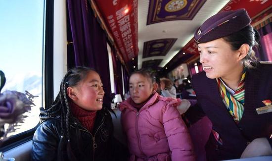 青藏铁路拉萨至日喀则段的藏族女列车长贡久曲珍(右)与乘客聊天(2020年1月12日摄)。 新华社记者 觉果 摄