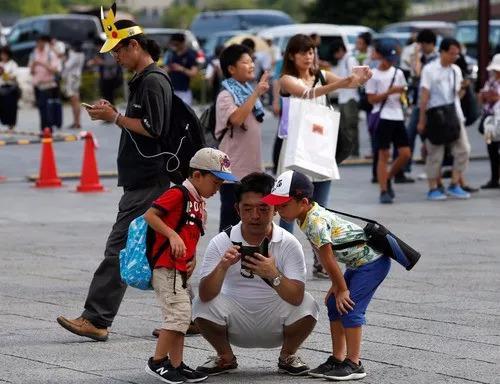 2017年8月9日,在日本横滨,人们用手机玩游戏。(新华社/路透)
