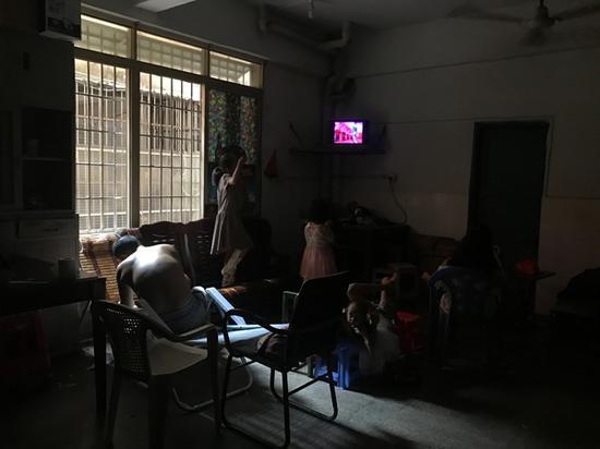 大大小小的女孩们围在一起,王忠馗弓着背坐在一旁。这间屋子是邻居借给一家十口暂住的。