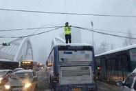 暴雪中 合肥交警爬上公交车顶托举电缆变“雪警”