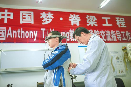 梁益建正在给患者调整治疗器。