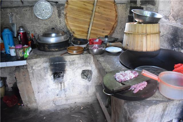 实拍农村人准备午餐，土灶上一口大铁锅，一边炒菜边劈柴