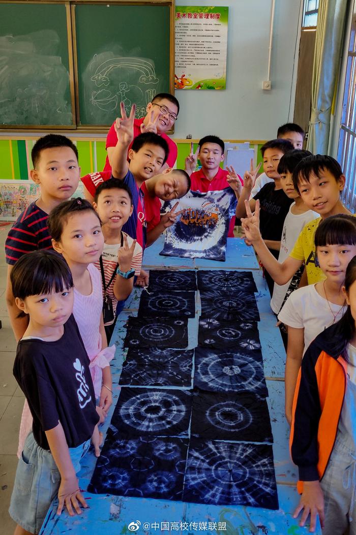 海南师范大学美术学院的志愿者们正在教授孩子剪纸，扎染，书法