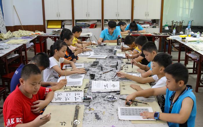 海南师范大学美术学院的志愿者们正在教授孩子剪纸，扎染，书法