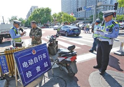 5月1日,宣武门路口,交警正在对一位有电动自行车临时标识但未悬挂的车主进行处罚。新京报记者 王贵彬 摄