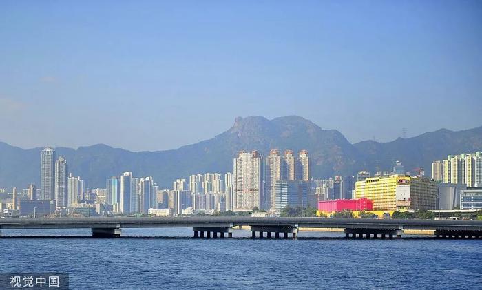(2014年11月21日,香港特别行政区观塘区,九龙湾一带的住宅建筑及商业楼宇,远处是香港的标志性景观——狮子山。图源:视觉中国)