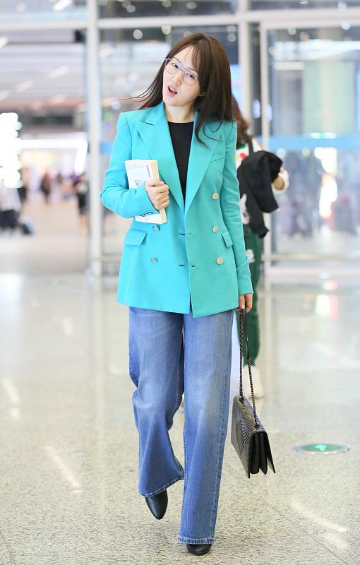 48岁杨钰莹素颜走机场 穿蓝色西装知性大方 拿书本娇羞挡脸
