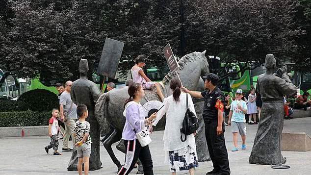 游客攀爬景区雕塑拍照, 保安喊话无效后, 竟默默地递上了一块牌子