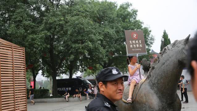 游客攀爬景区雕塑拍照, 保安喊话无效后, 竟默默地递上了一块牌子