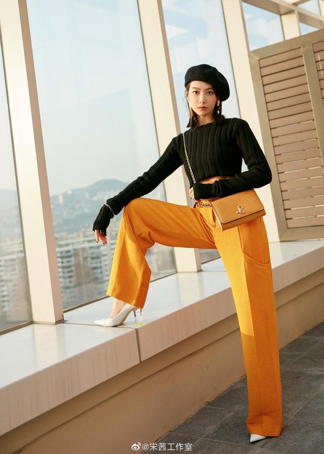 宋茜身穿橘色高腰阔腿裤搭黑色短毛衣，演绎都市女性街头新风尚。