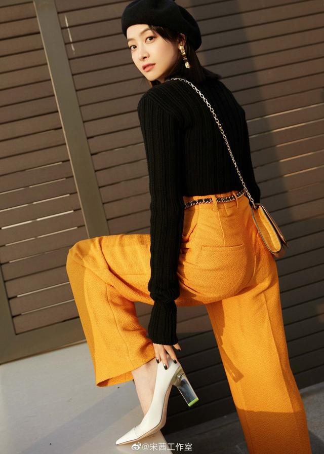 宋茜身穿橘色高腰阔腿裤搭黑色短毛衣，演绎都市女性街头新风尚。