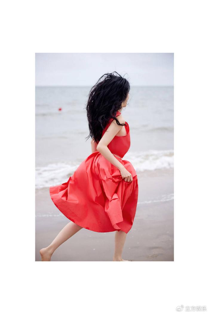 张俪穿红色长裙赤脚漫步海边 海风吹动长发回眸氛围感拉满