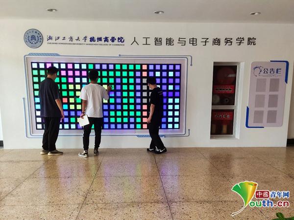 图为学生在say hi墙面前驻足试玩。